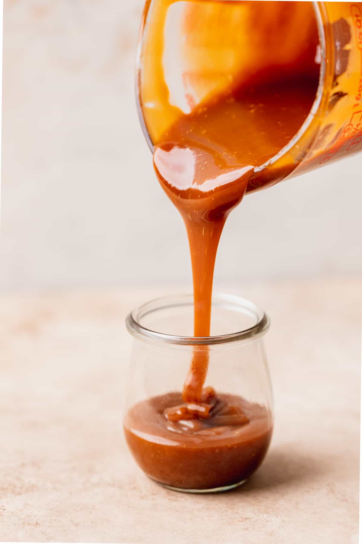 Pouring caramel in a glass jar.