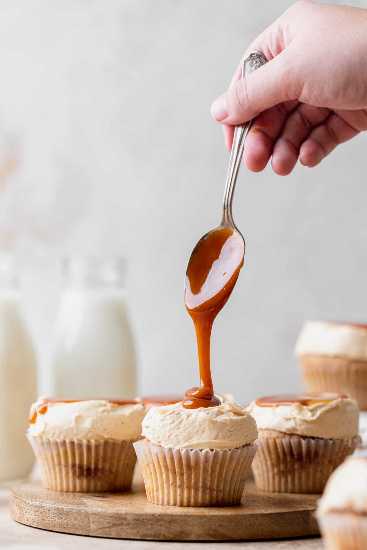 Pouring caramel on top of cupcakes.