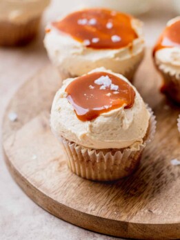 Salted caramel cinnamon cupcakes on a wood plate.