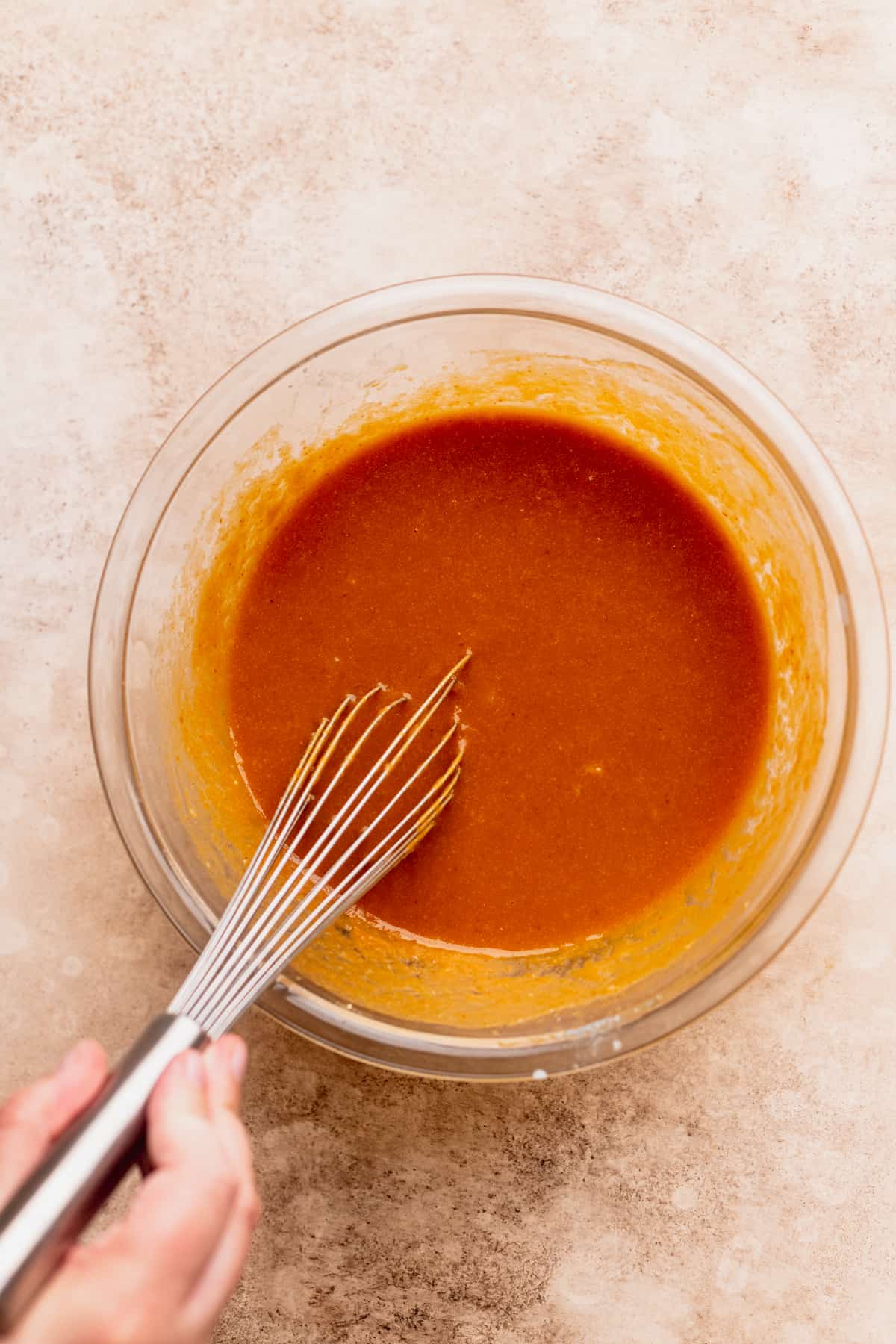 Mixing wet ingredients in a glass bowl.