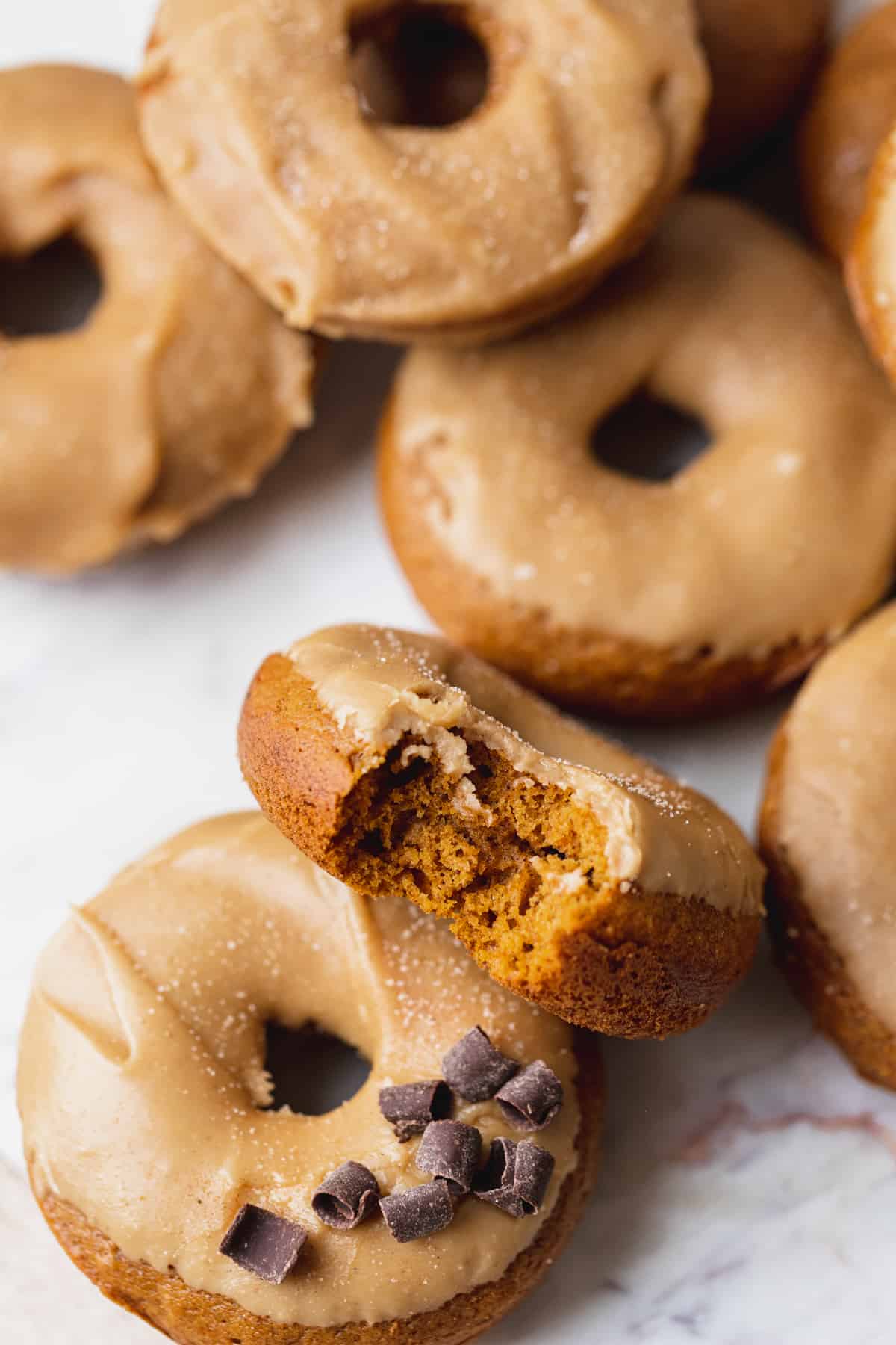 A bite missing from maple pumpkin donuts.