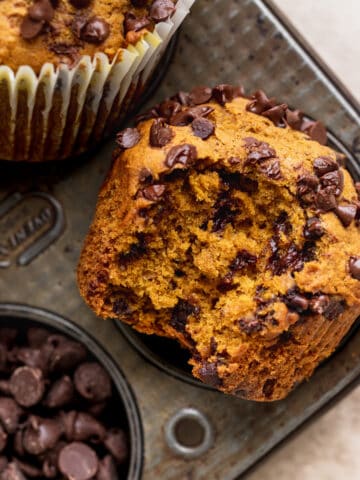 Bite missing from pumpkin chocolate chip muffins.