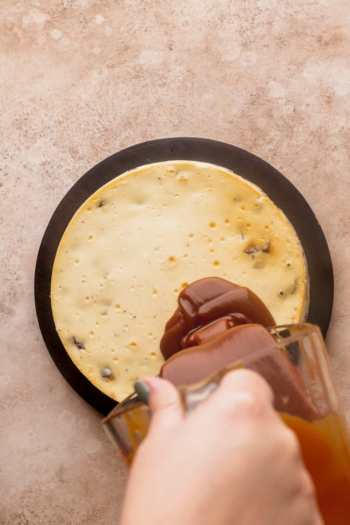 Pouring caramel on top of cheesecake.