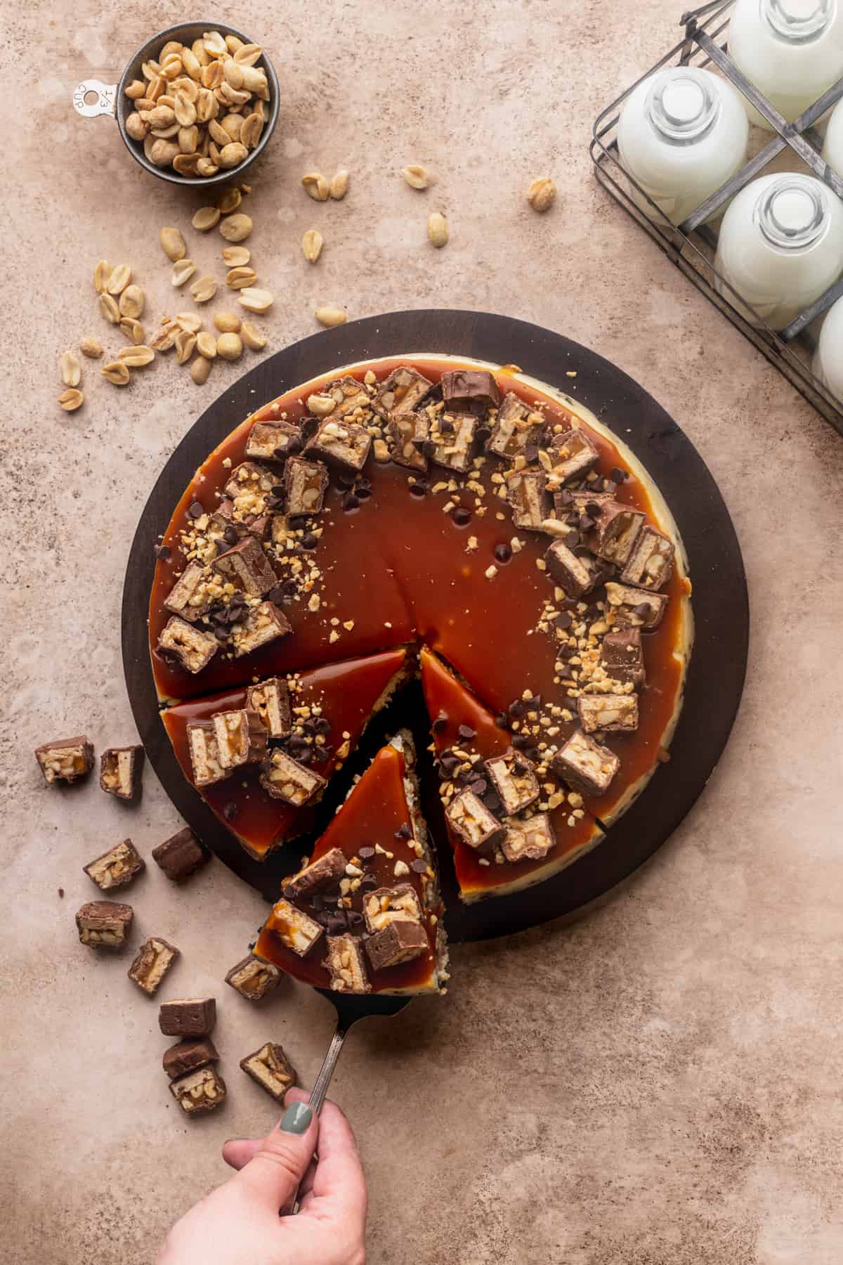 Snickers cheesecake cut into thirds pulling one pieces out.