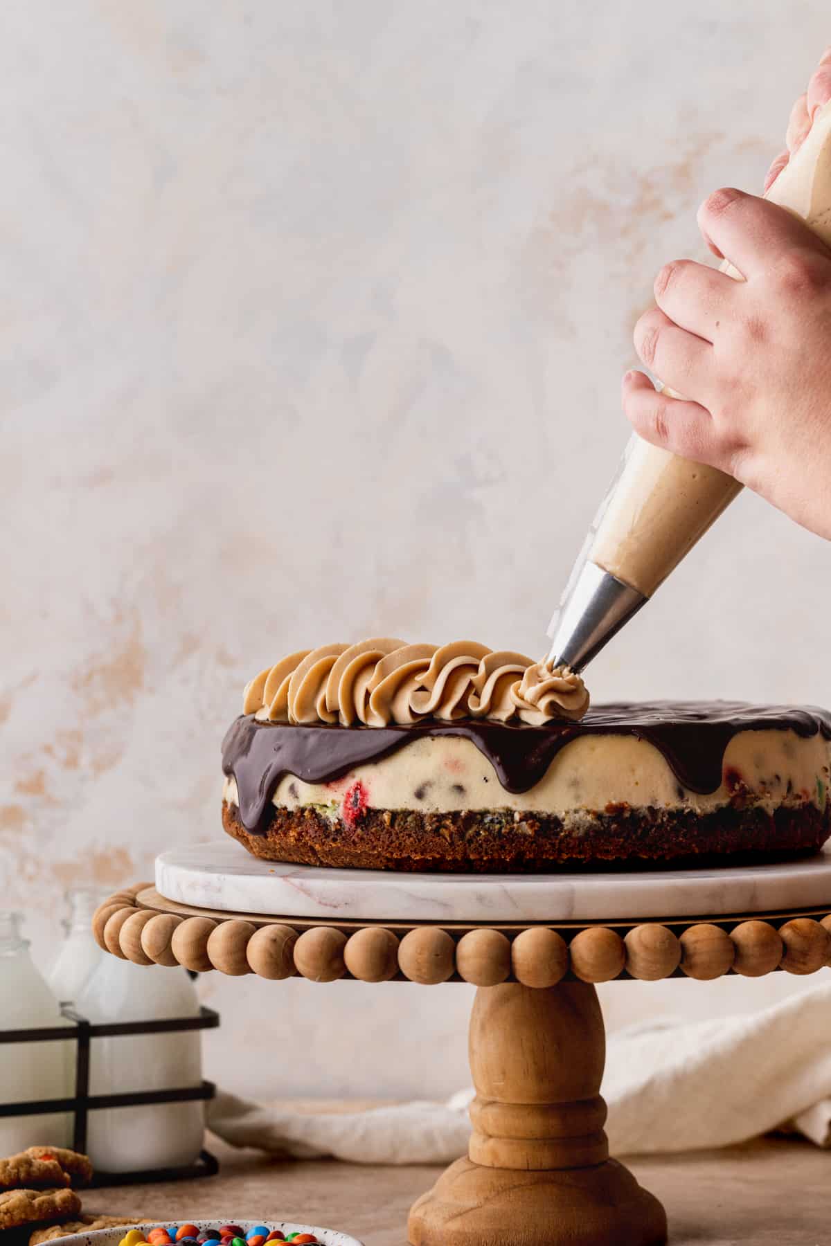 Piping peanut butter frosting on cheesecake.