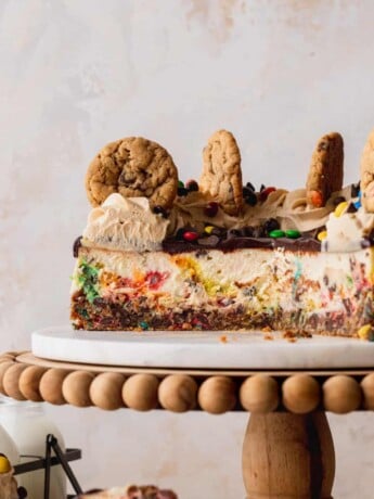 Monster cookie cheesecake cut in half on a cake stand.