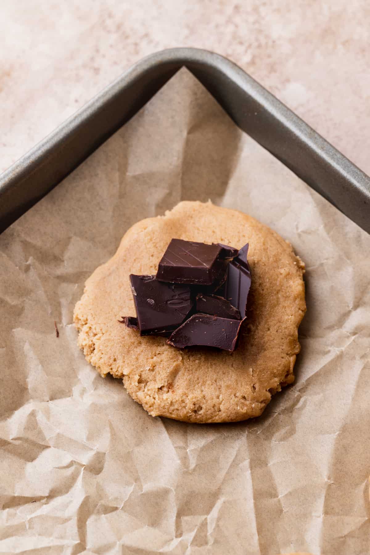 Chopped chocolate on flattened cookie dough.