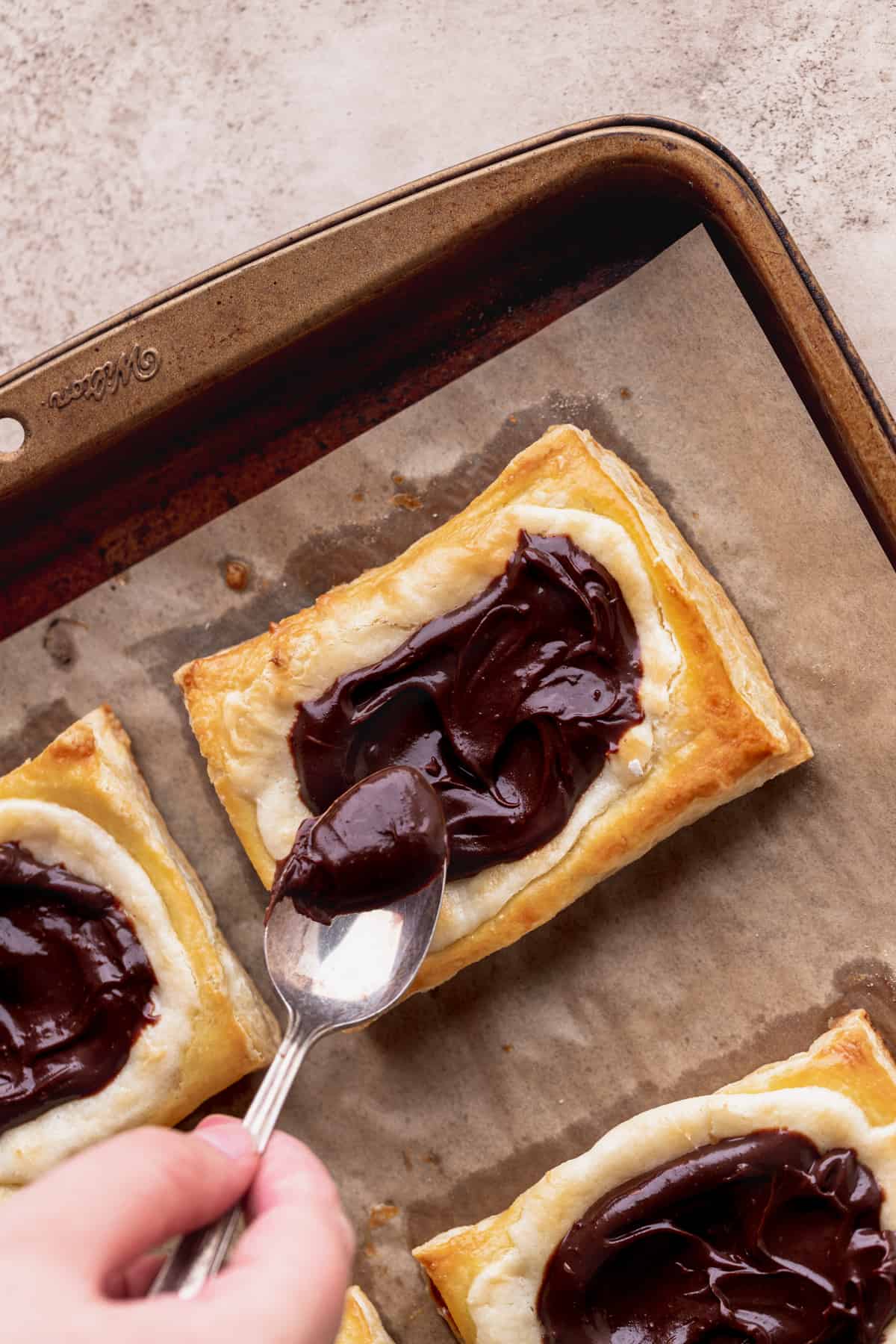 Spreading chocolate on top of pastry.