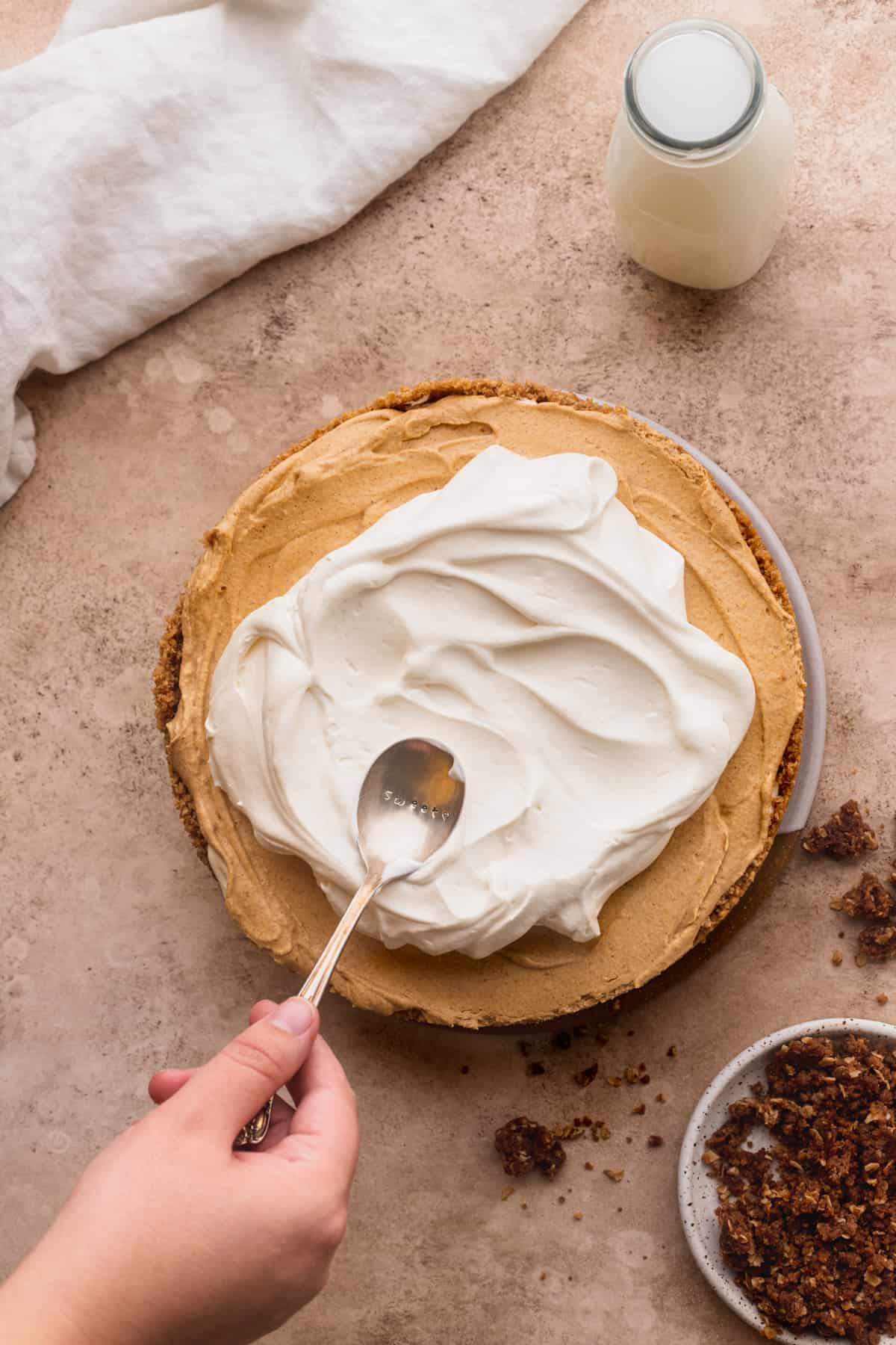 Spreading whipped cream on top of cheesecake.