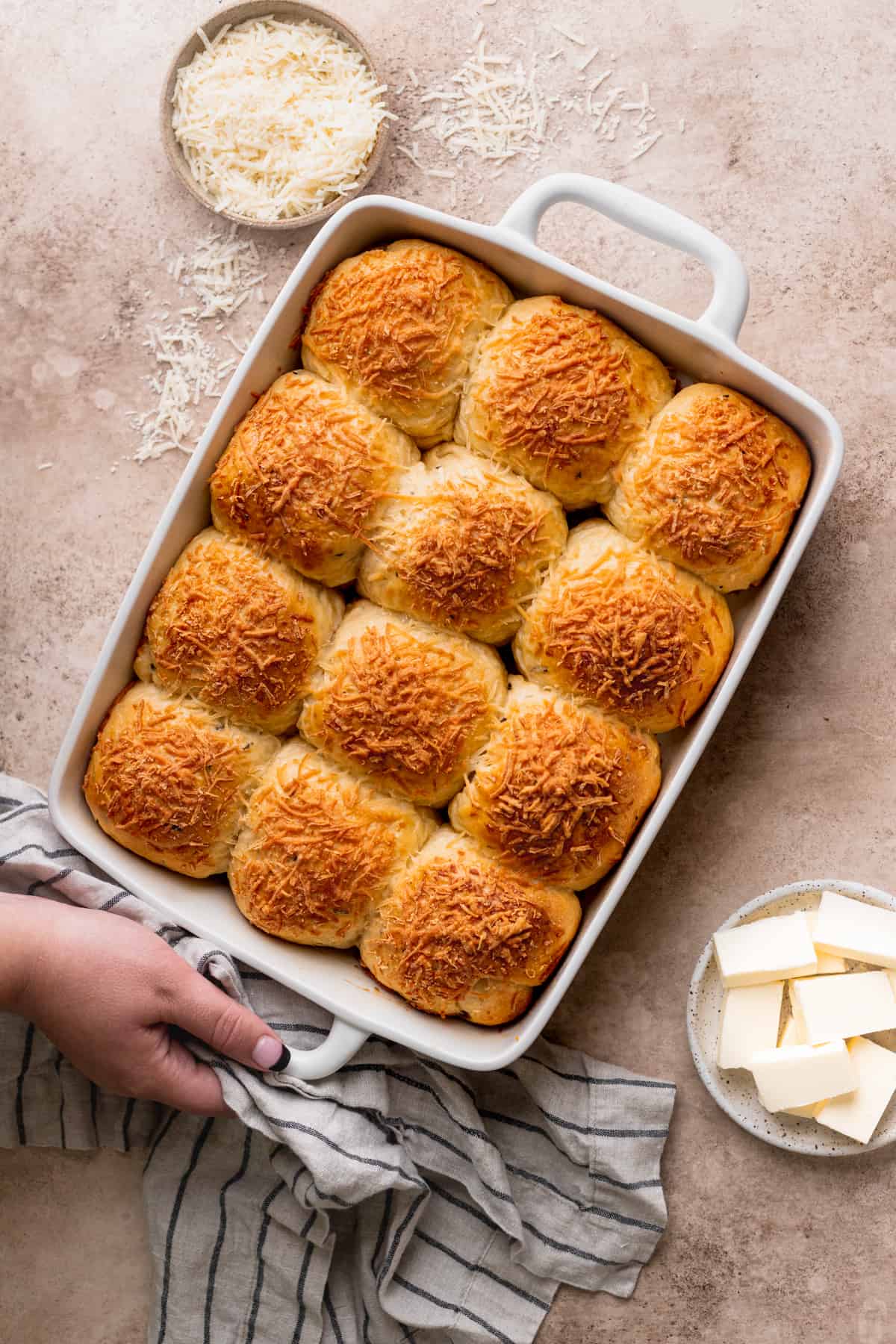 A hand on top of pan full of rolls.