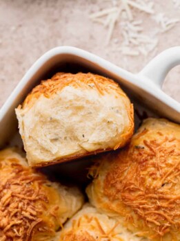 Fluffy cheddar cheese rolls with one on its side.