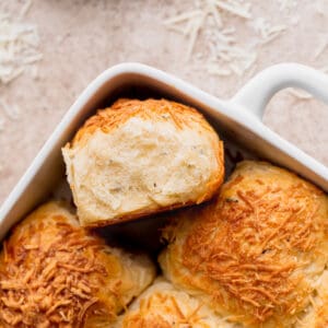 Fluffy cheddar cheese rolls with one on its side.