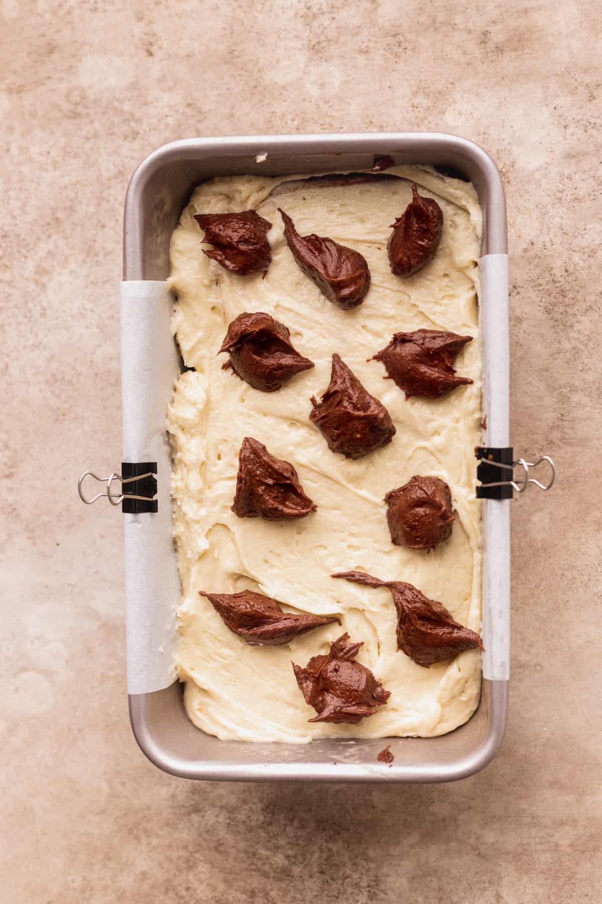 Dollops of chocolate cake batter on top of pan.