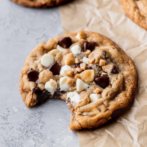 Bite missing from white chocolate toffee cookies.
