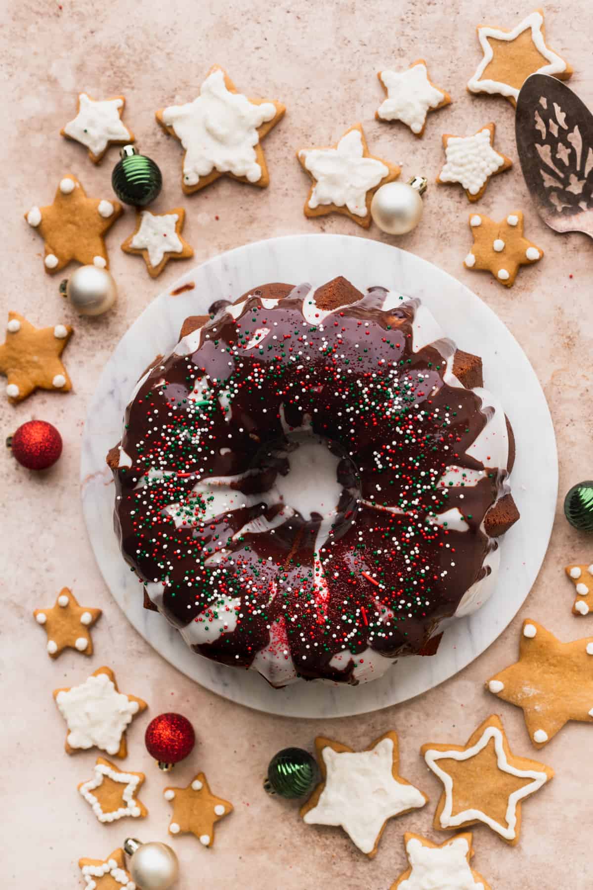 Gingerbread bundt cake on a marble board surronded by gingerbread cookies.