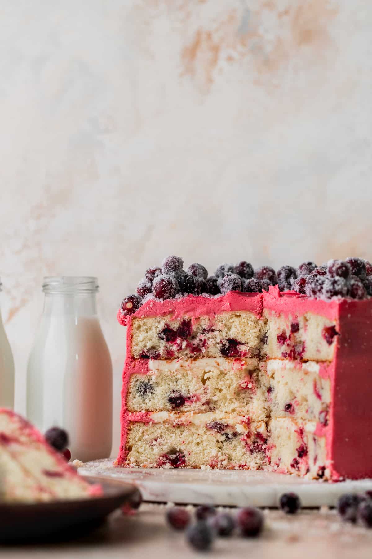 Three layers of Christmas cranberry cake on a board.