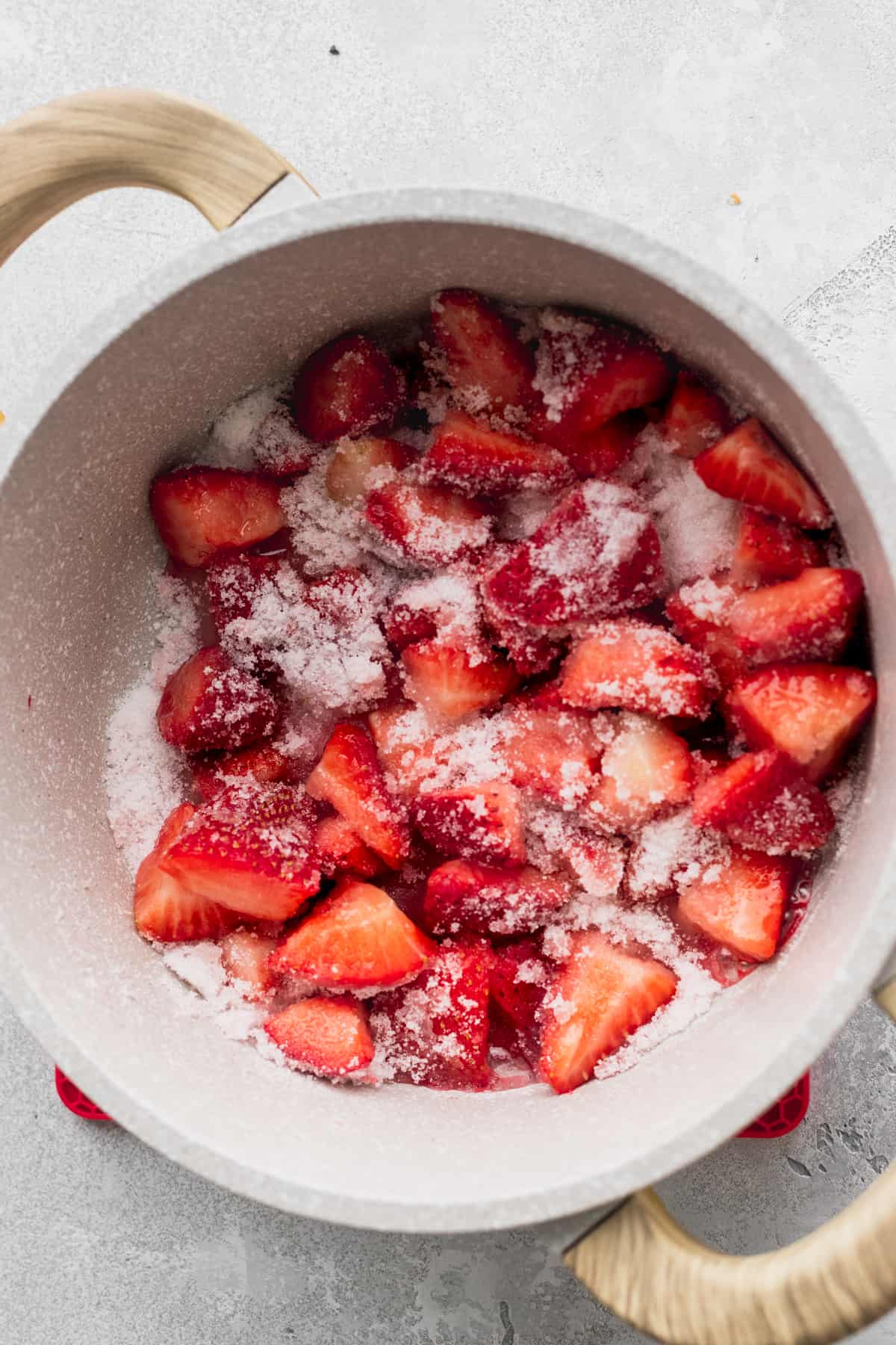 Strawberries covered in sugar in a pot.