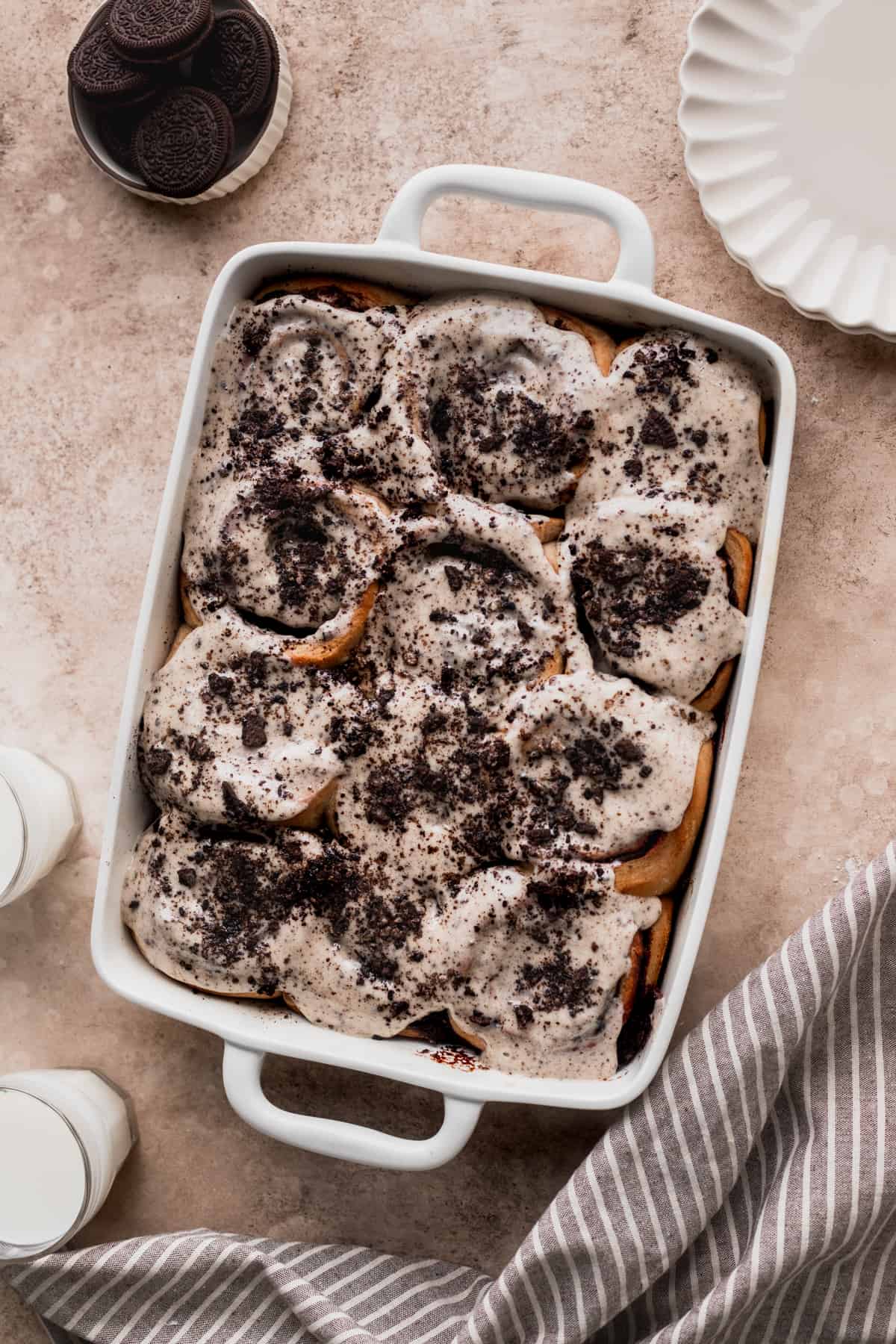 Cookies and cream cinnamon rolls in a platter with glasses of milk on the side.