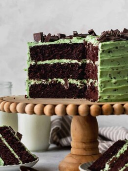 Chocolate mint cake on a cake stand with cake slices around it.