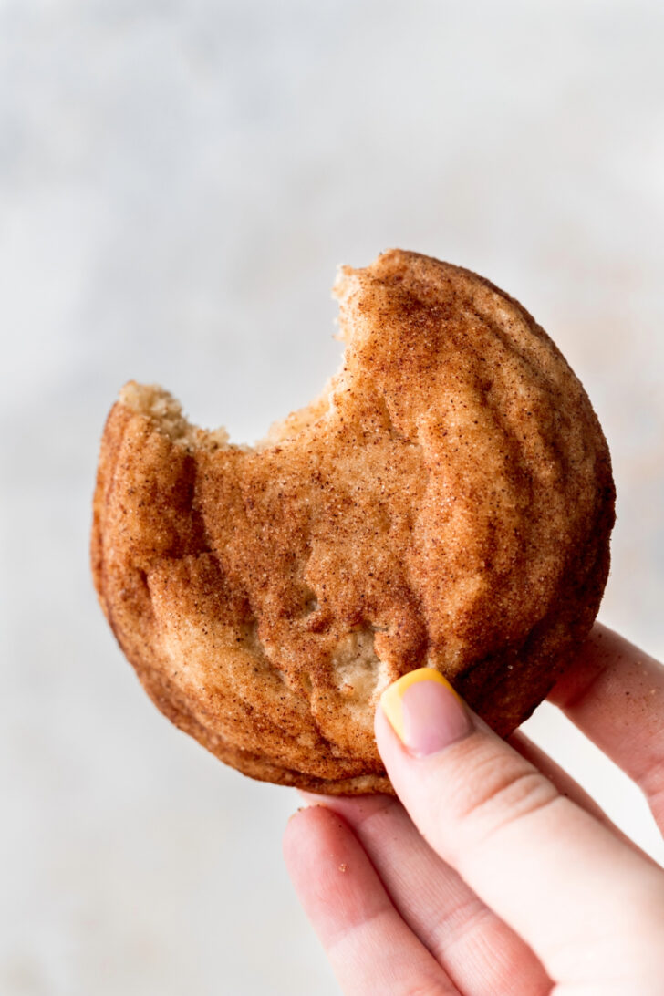 Holding a cookie with a bite missing.