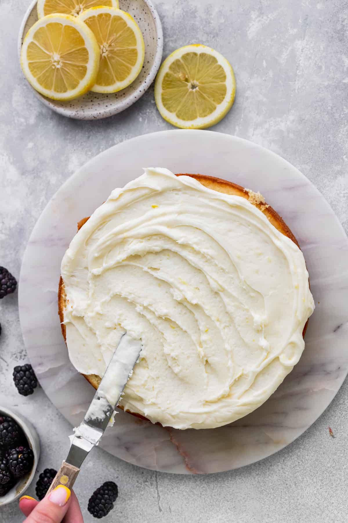 Spreading lemon frosting on top of cake.