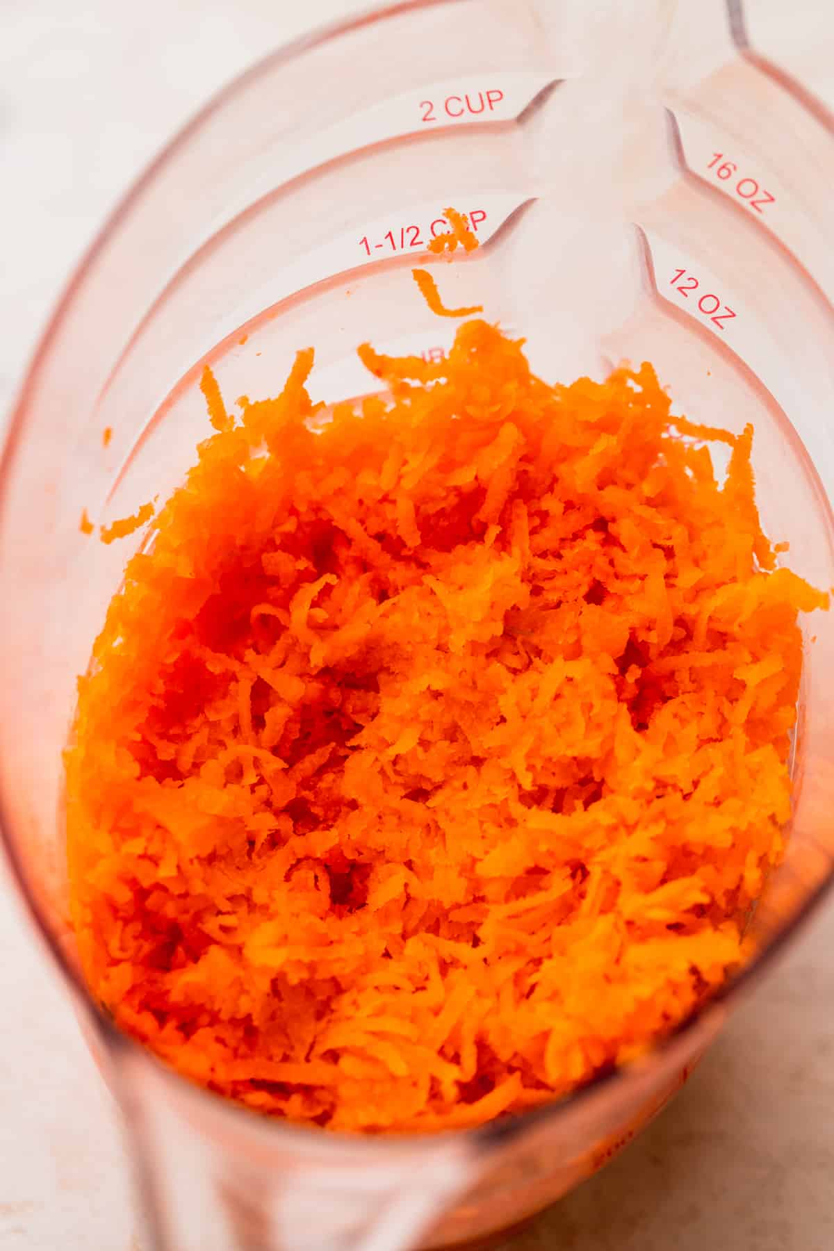 Shredded carrots in a measuring cup.