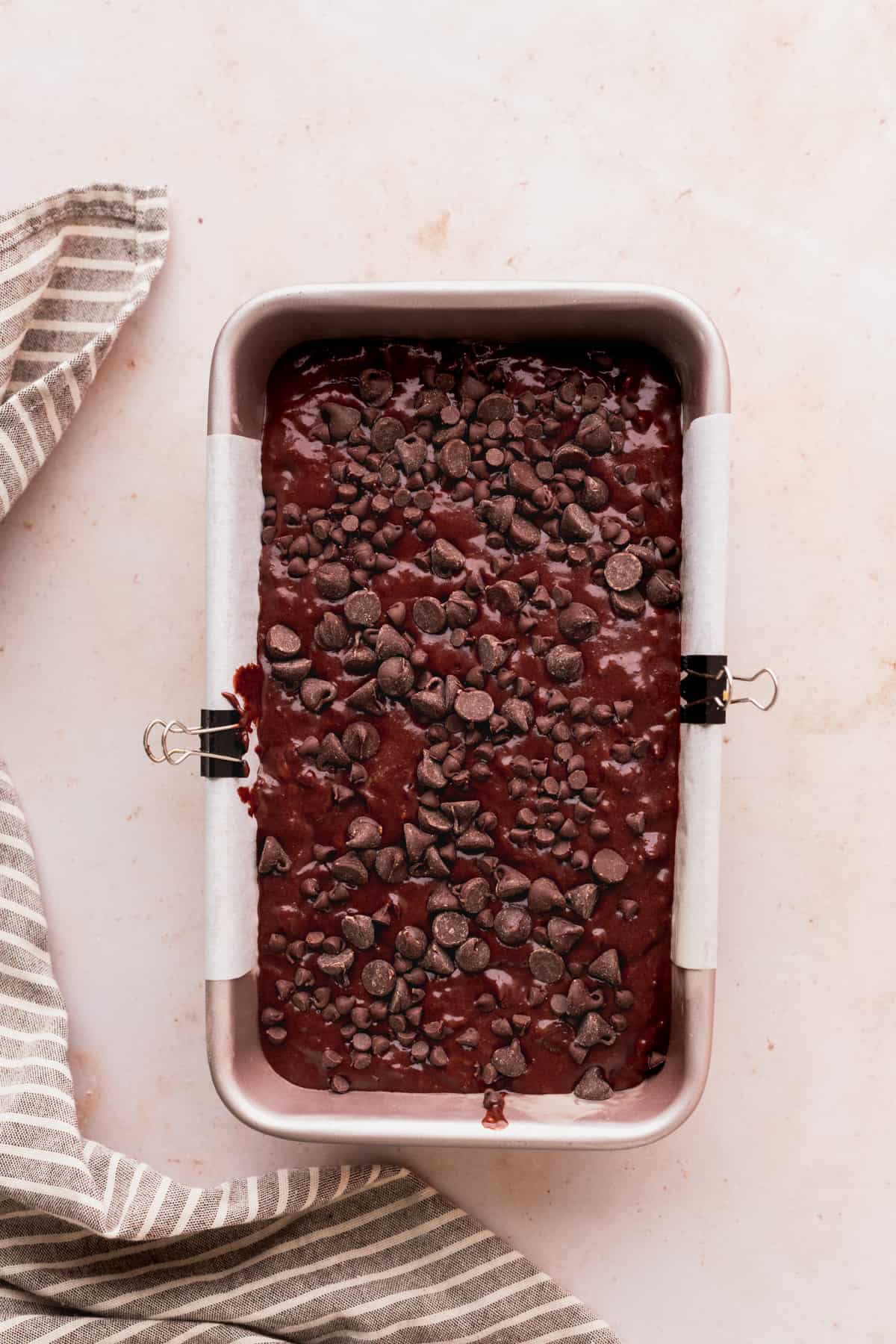 Banana bread batter in a loaf pan with extra chocolate chips on top.