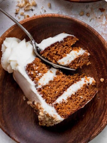 One slice of cake on a wood plate with a fork inserted.