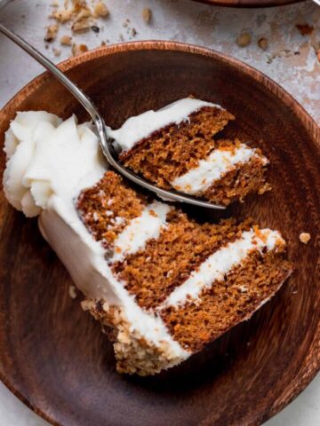 One slice of cake on a wood plate with a fork inserted.