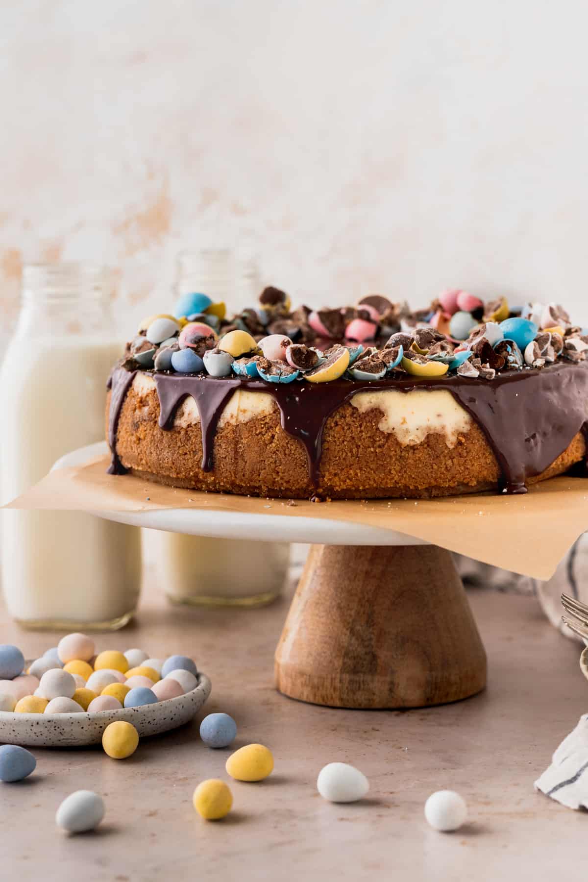 Easter egg cheesecake on a cake stand surrounding by mini eggs.
