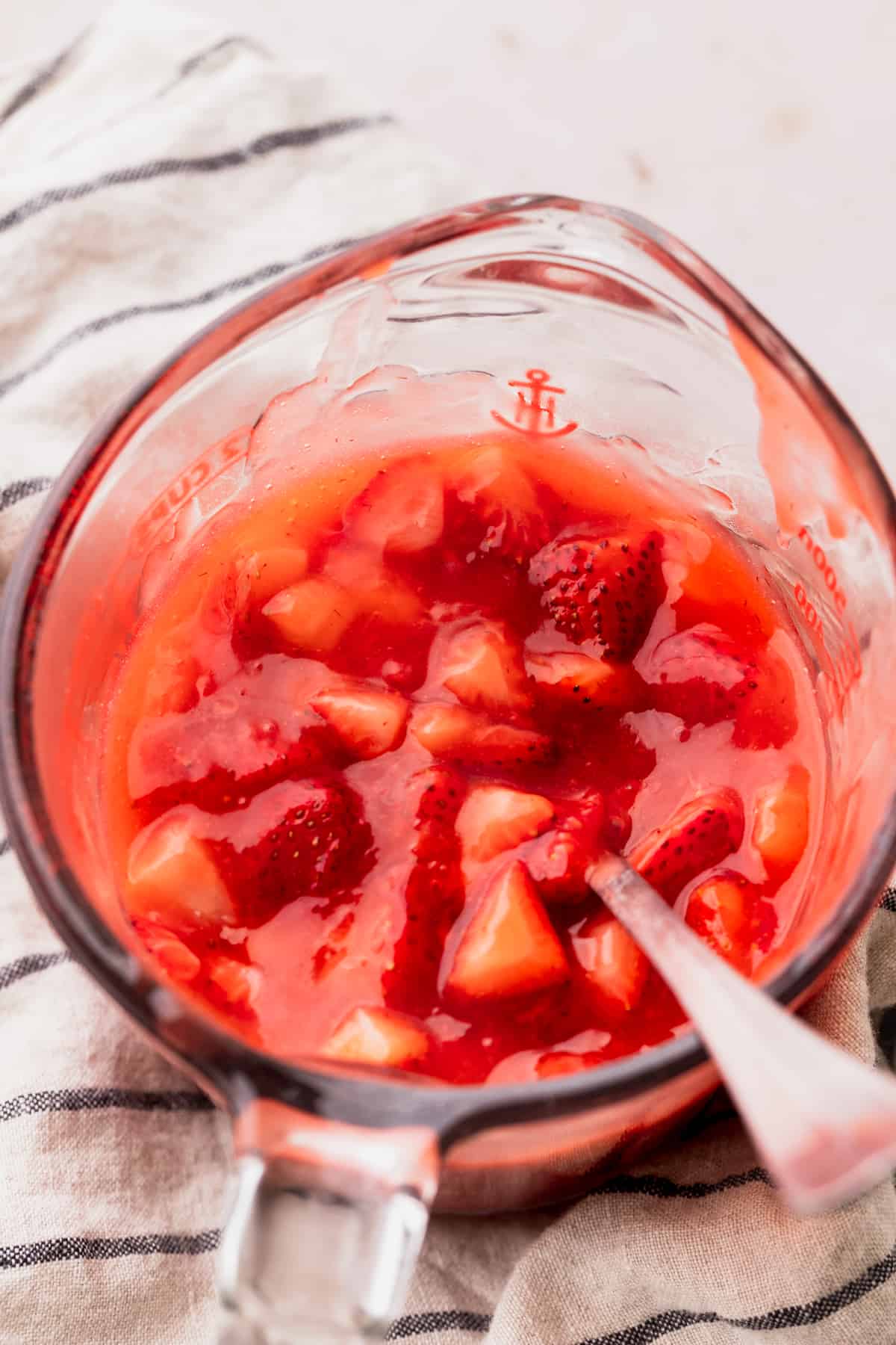 Strawberry preserves in a wet measuring cup.