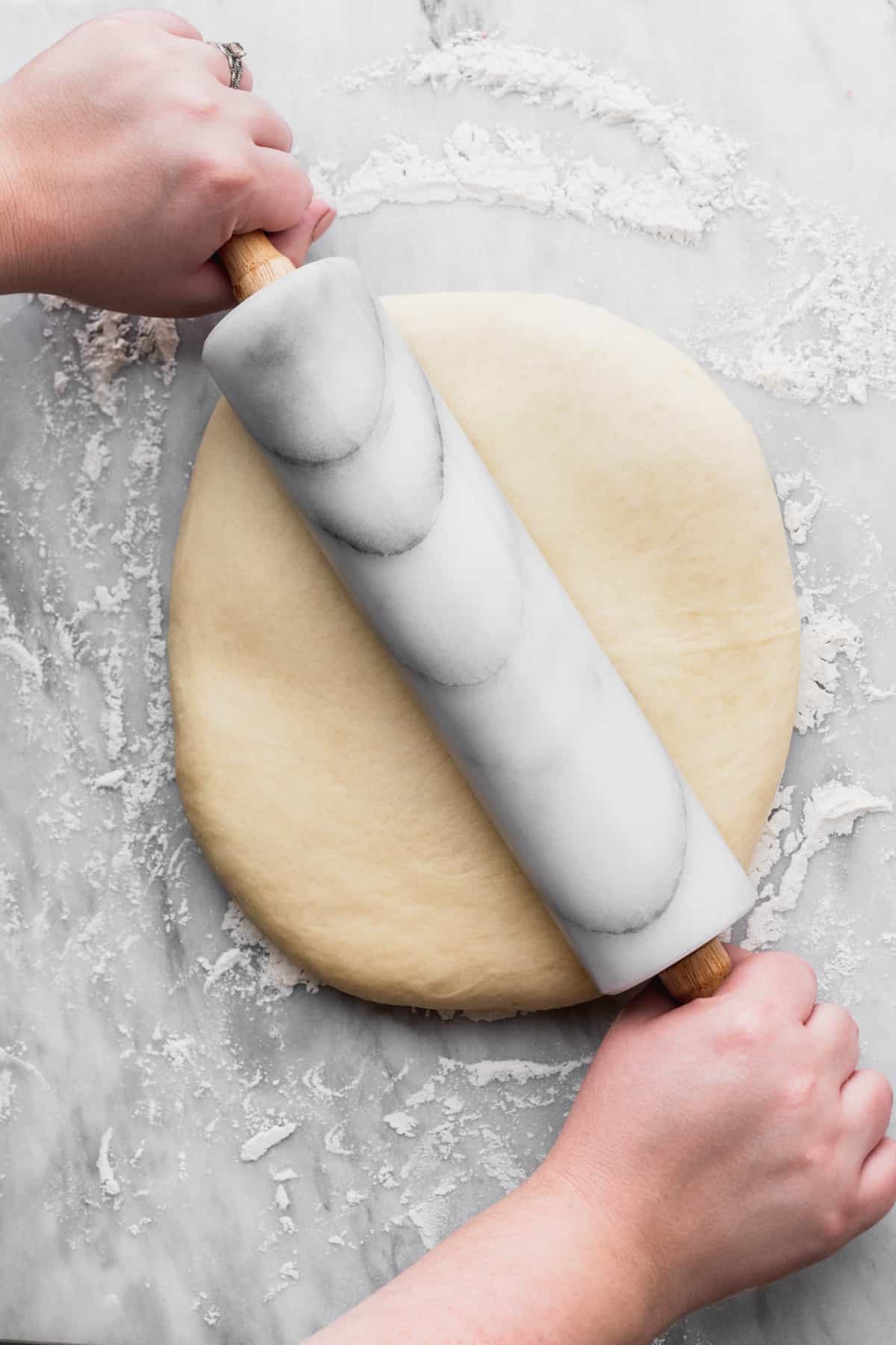 Rolling out the dough using a rolling pin.