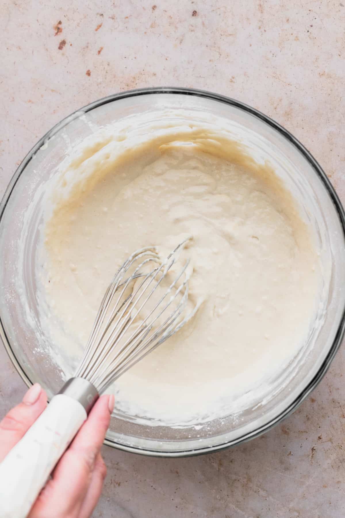 Mixing pancake batter in a glass bowl.