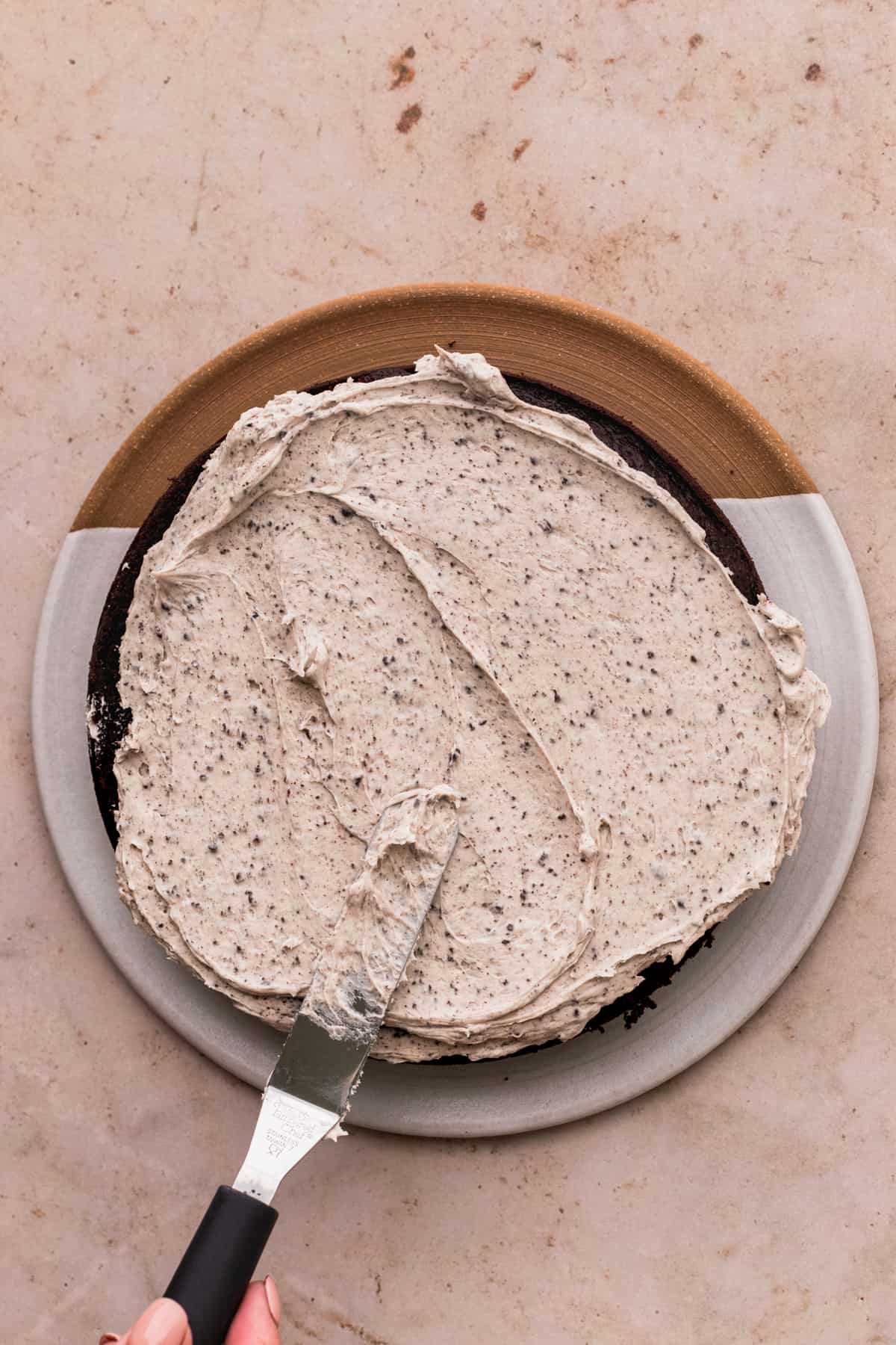 Spreading Oreo frosting on top of cake layer.