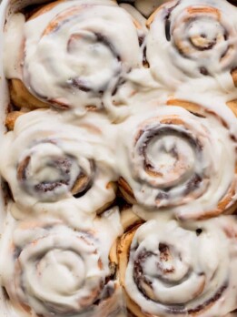 Giant fluffy cinnamon rolls in a pan with a spatula beside it.