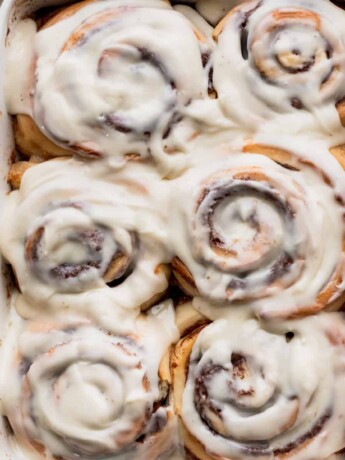 Giant fluffy cinnamon rolls in a pan with a spatula beside it.