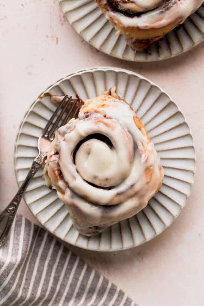 1 cinnamon roll on a plate with a fork.