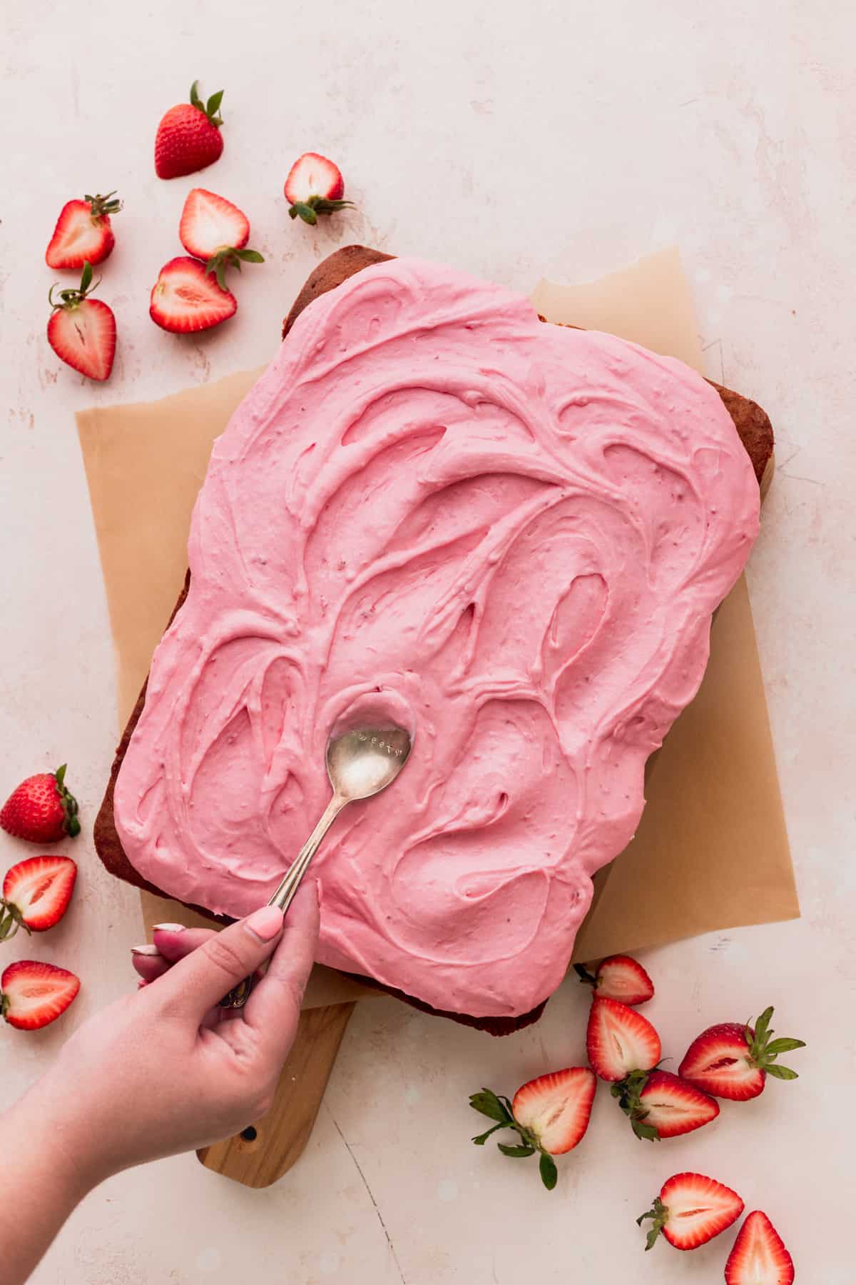 Spreading the strawberry frosting on top of the cake.