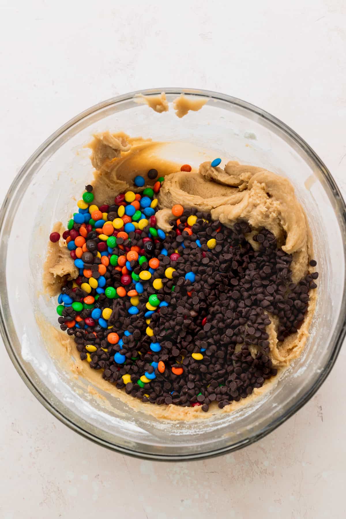 Cookie dough in a glass bowl with mini m&ms on top.