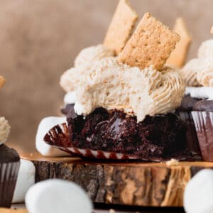 A bite missing from s'mores cupcakes on a wooden board.