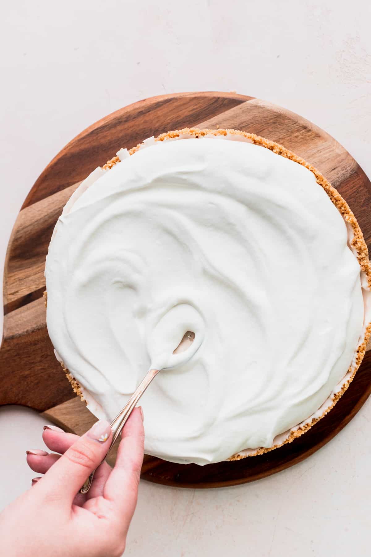 Spreading whipped cream on top of cheesecake.
