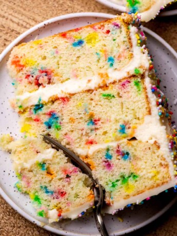 Fork inserted into a cake slice on a plate.