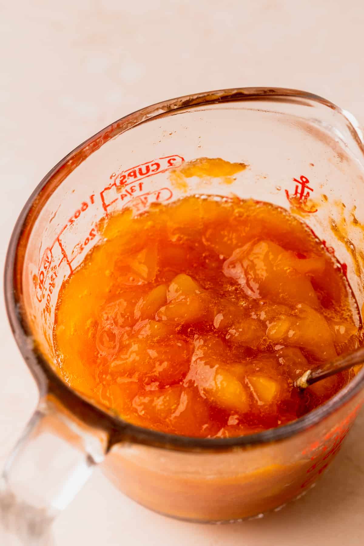 Peach jam in a measuring cup.