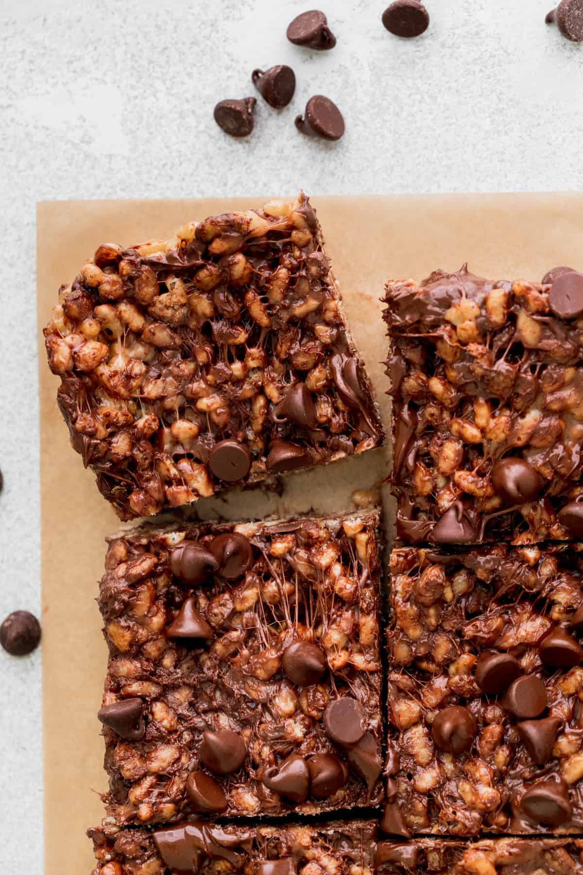 One slice of chocolate rice krispie treats pulled away on parchment paper.