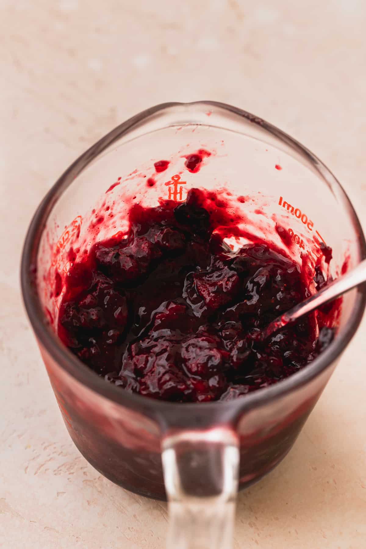 Strawberry blueberry jam in a glass measuring cup.