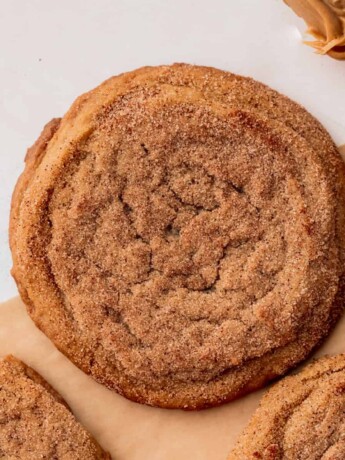 Chewy peanut butter cookie dipped in cinnamon sugar on parchment paper.