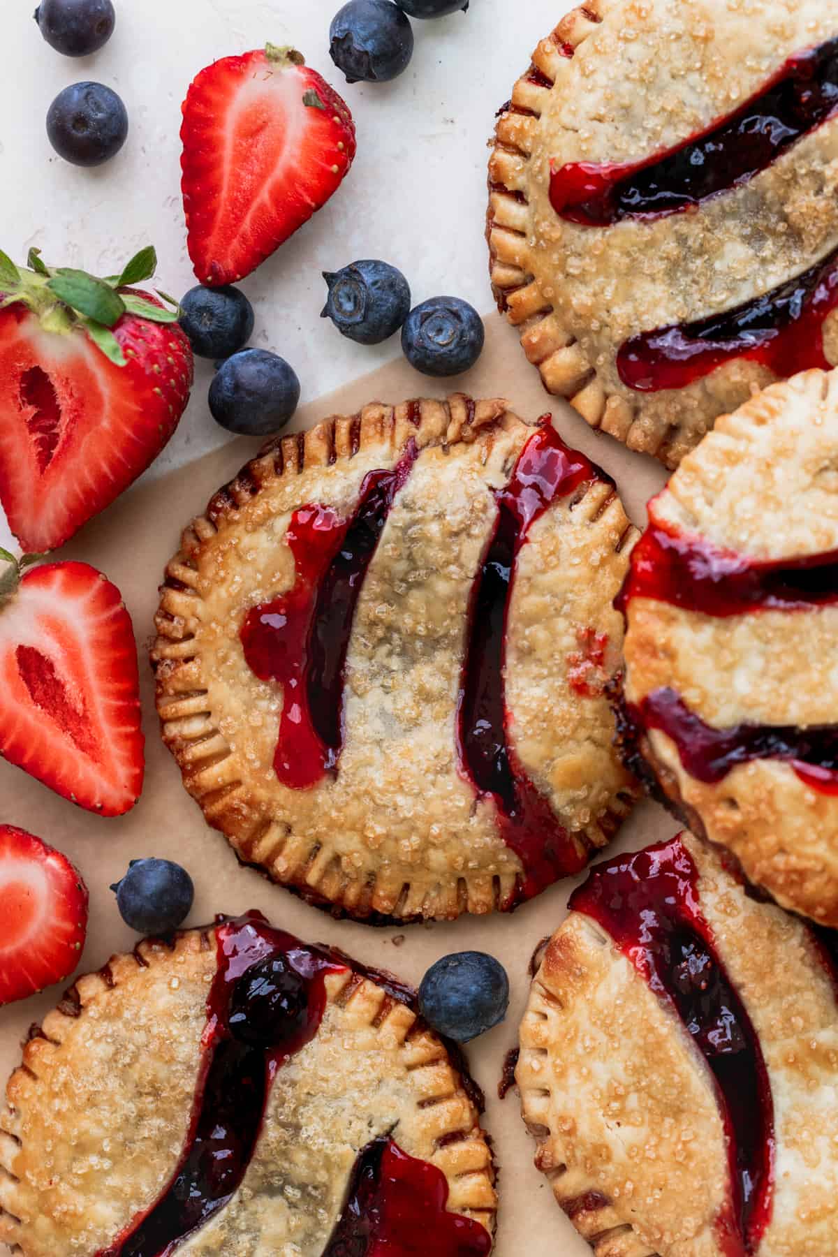 Pies on parchment paper with fresh berries.