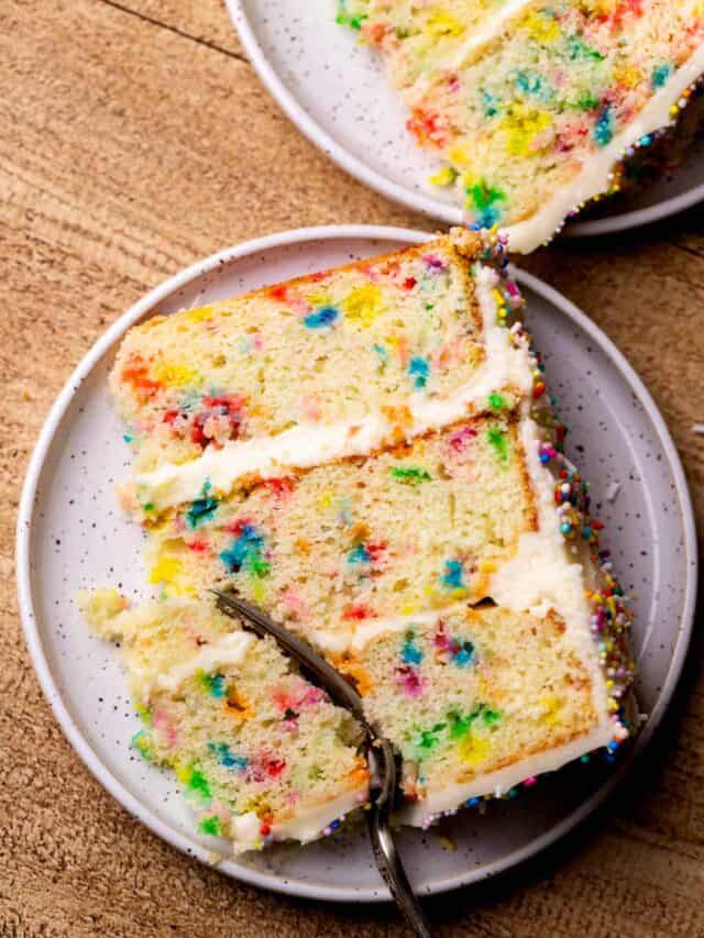 Fork inserted into a cake slice on a plate.