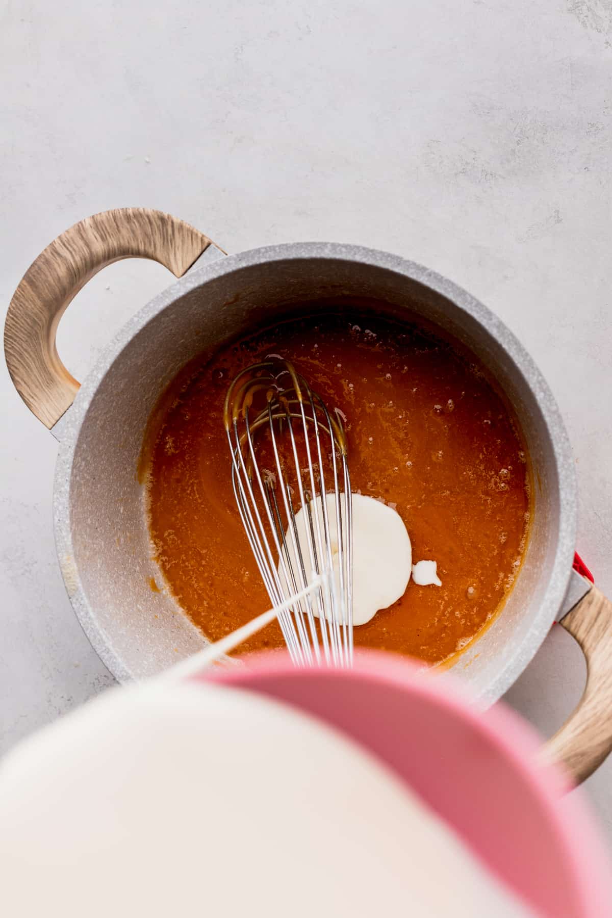 Pouring heavy cream into a pot.