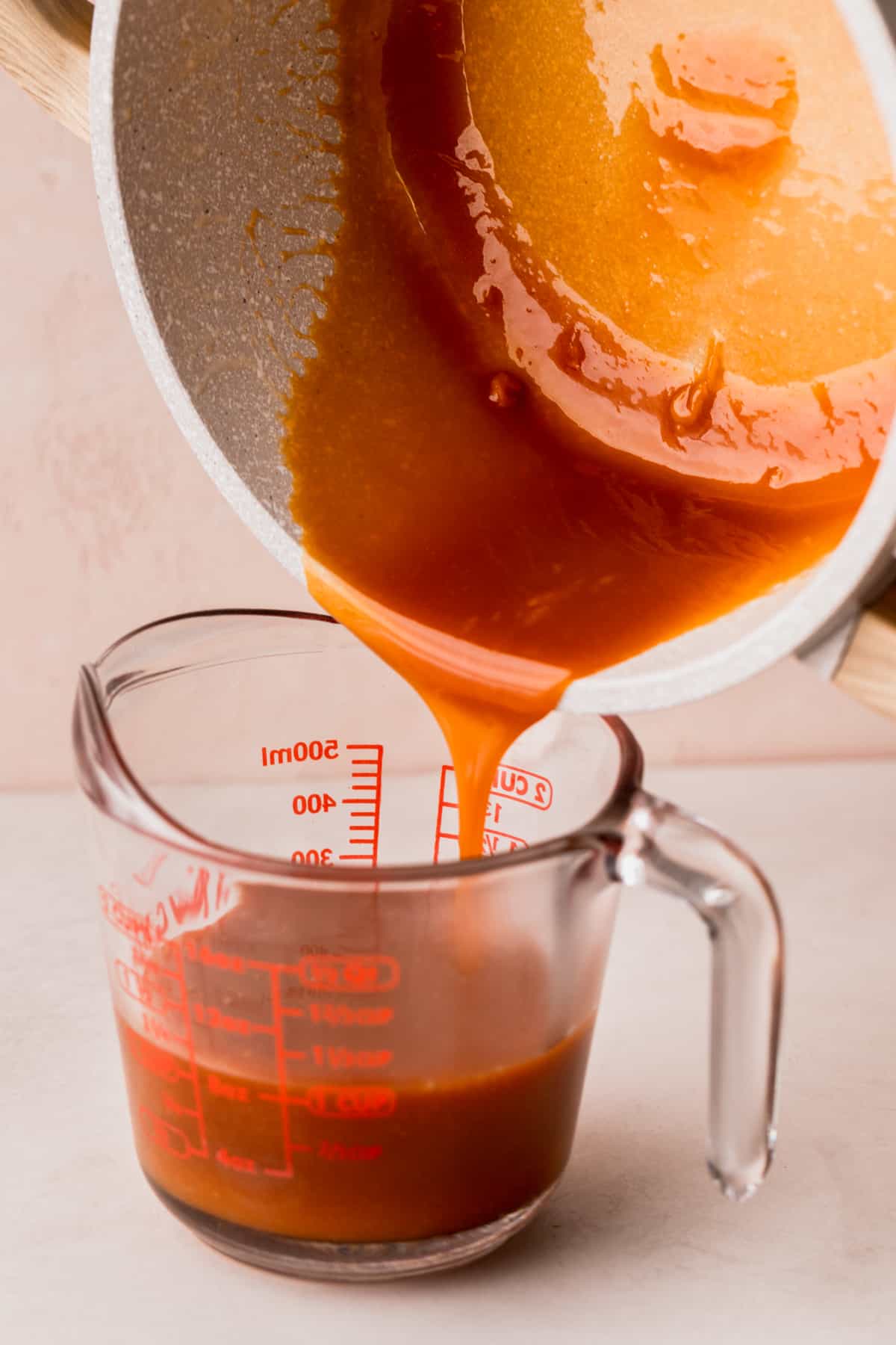 Pouring a hot caramel into a glass container.